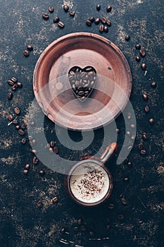 Heart of coffee beans and hot coffee drink in a vintage cup on a rustic dark background. Valentine`s Day.Top view, place for text