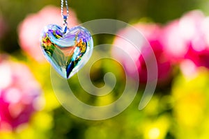 Heart crystal glass refract sunlight - rose garden background