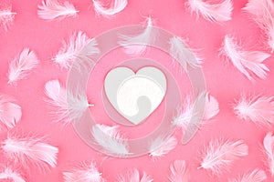 Heart and delicate fluffy white feathers on pink paper background. Mothers Women\'s Day. Love tendernes photo