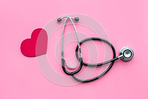 Heart disease concept. Stethoscope near heart sign on pink background top view