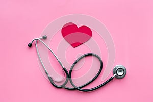 Heart disease concept. Stethoscope near heart sign on pink background top view