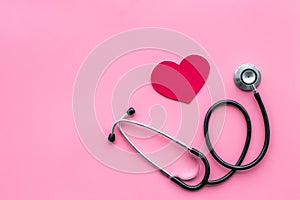 Heart disease concept. Stethoscope near heart sign on pink background top view copy space