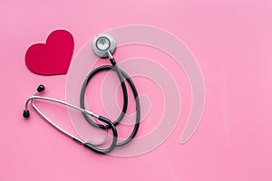 Heart disease concept. Stethoscope near heart sign on pink background top view copy space