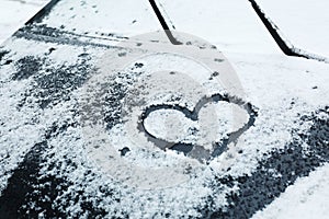 Heart drawn on car covered with snow, closeup.