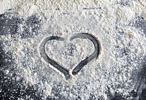 The heart is drawn on flour scattered on a dark table