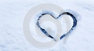 Heart drawn by hand on car window covered with deep snow.