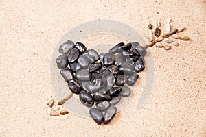 Heart drawn with pebbles on the beach sand