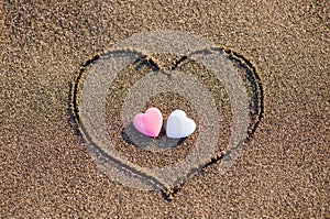 Heart drawn in the sand with two hearts