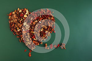 Heart from dry fragrant flowers on a green background