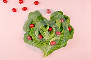 Heart of fresh leaves greens salad and cherry tomatoes on pink background.