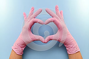  Heart gesture with hands in pink latex protective gloves on a blue background.