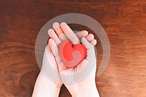 Heart in hand for philanthropy concept - woman holding red heart on hands for valentines day or donate help give love warmth take photo