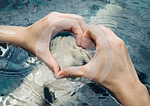 Heart from hands on swimming pool