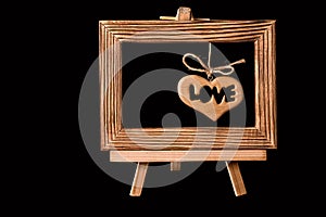 Heart hanging in old picture frame on black background