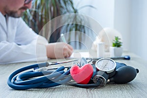 Heart health and diagnosis and treatment of cardiac disease concept photo. In foreground figure of red heart surrounded by stethos