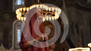 In the heart of Istanbul, a scarf-clad woman tourist stands before Ayasofya's timeless grandeur, her gaze captivated