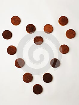 Heart laid out of espresso coffee pucks on white background. Isolated, top view