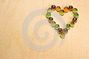 The heart is lined with glass stones on a wooden background