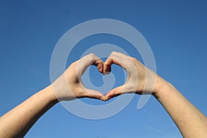 Heart of love with hands in blue sky