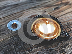 Heart love Latte art coffee in black cup on  vintage wooden table. Coffee Lover.