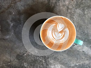 Heart love shape latte art coffee in white and green cup on cement background with natural light