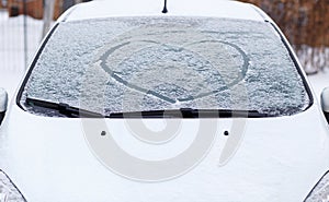 Heart love symbol on windscreen of car in snow