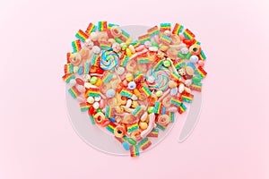 Heart made of colorful sugar candies on a pink background. Valentine's Day concept. Top view, flat lay.