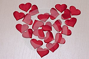 The heart is made of decorative hearts on a wooden surface. Valentine`s Day decoration. The photo