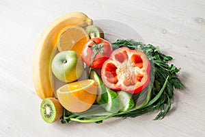 Heart made from different fruits and vegetables on light wooden table