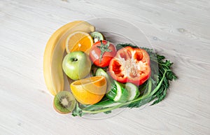 Heart made from different fruits and vegetables on light wooden table