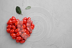 Heart made of fresh goji berries and leaves on background, flat lay. Space for text