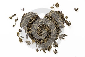 Heart made of green dry tea, on white background