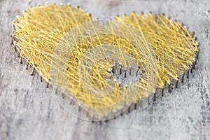 Heart made of nails on wood with wowen gold string