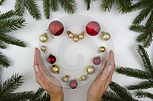 Heart made out from Christmas decorations and woomen hands. White background christmas balls.Flat lay