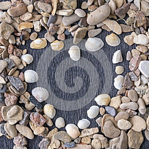 Heart made of sea shells and gravel over wooden textured background, closeup. Romance and tropical holiday concept.