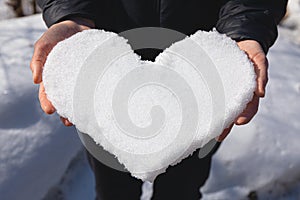Heart made of snow in female hands. Winter entertainment