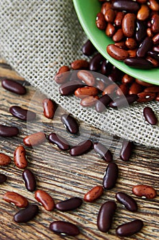 The heart made with sprinkled beans a mix of red beans and roman beans on a rustic wooden table with canvas and green bowl