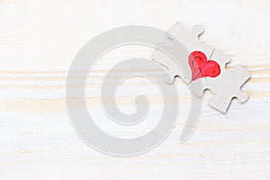 Heart made of two pieces of jigsaw puzzle on light wooden table, copyspace for text