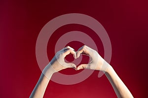 Heart made up of female hands on a red background