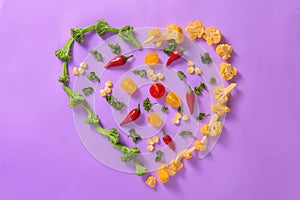 Heart made of various vegetables on color background