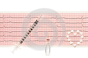 Heart made of white heart shape tablets, transparent white glass ampoule with a drug and plastic syringe on paper ECG results
