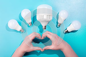 heart from male hands big LED light bulbs on blue color background with little led lamps