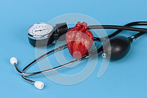 Heart and mechanical blood pressure monitor on a blue background. Measurement and control of blood pressure
