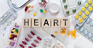 HEART medicine word on wooden blocks on a desk. Medical concept with pills  vitamins  stethoscope and syringe on the background