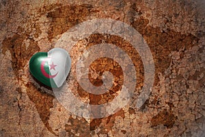 Heart with national flag of algeria on a vintage world map crack paper background.