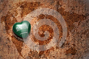 Heart with national flag of saudi arabia on a vintage world map crack paper background.