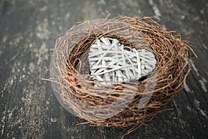 Heart in nest on wooden background in country style.