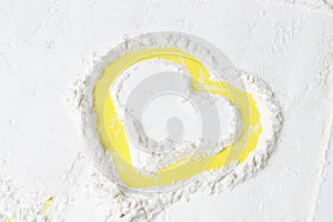 Heart painted on scattered flour, a yellow background