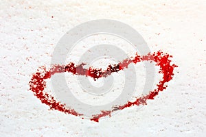 Heart painted on the snow-covered windshield of a car.