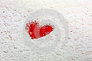 Heart painted on the snow-covered windshield of a car.